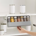 Pull-out spice rack mounted under a kitchen cabinet shelf with spice jars